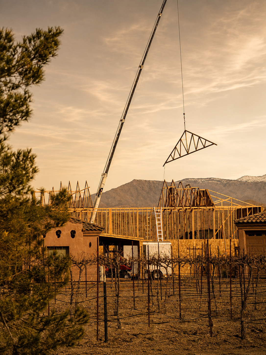 Crane lifting a roof truss during construction at Quail Rock Vineyard at sunset